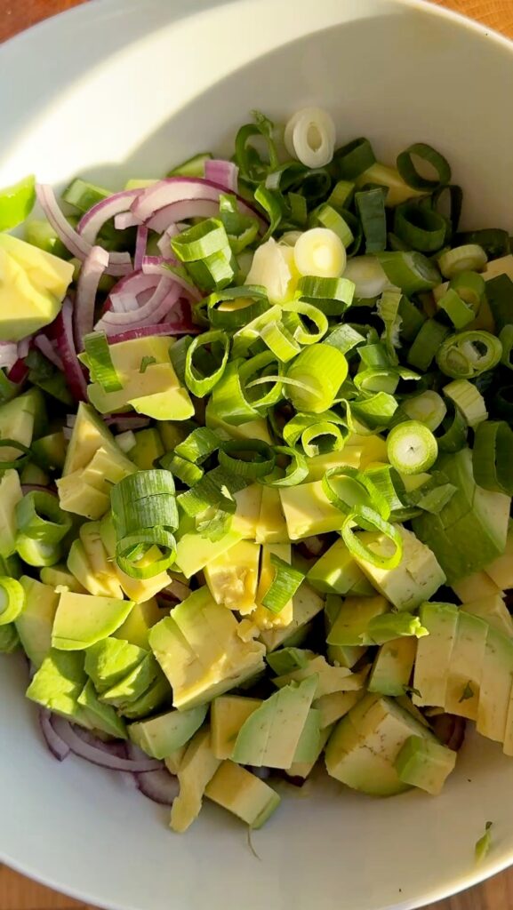 chop the cucumbers, avocado, red onion, spring onion, cilantro, and mint. Combine all the vegetables in a large salad bowl.