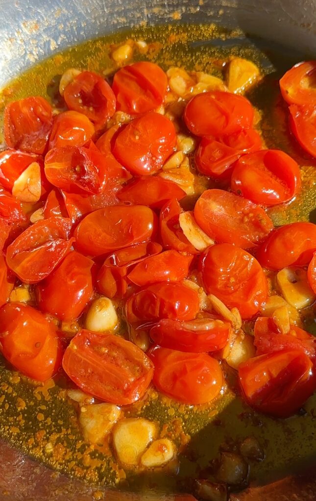 While the eggplant is baking, heat 2 tbsp olive oil in a pan over medium heat.
Add the sliced garlic and sauté for about 1 minute until fragrant.
Add the halved cherry tomatoes, season with salt and black pepper, and cook for 5–7 minutes