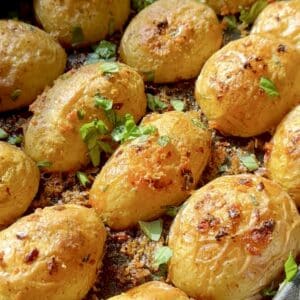 Golden Parmesan crusted potatoes topped with fresh basil, crispy on the outside and soft inside, ready to serve as a flavorful side dish.