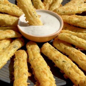 Golden baked potato cheese sticks served on a plate, crispy on the outside and cheesy inside, with garlic yogurt sauce on the side.