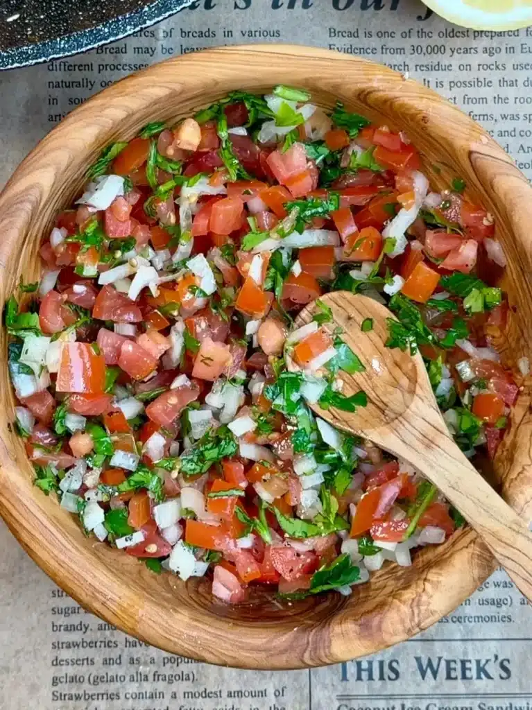 Fresh salsa with diced tomatoes, onion, and cilantro for Cheesy Loaded Taco Fries, seasoned with lemon juice, salt, and pepper.