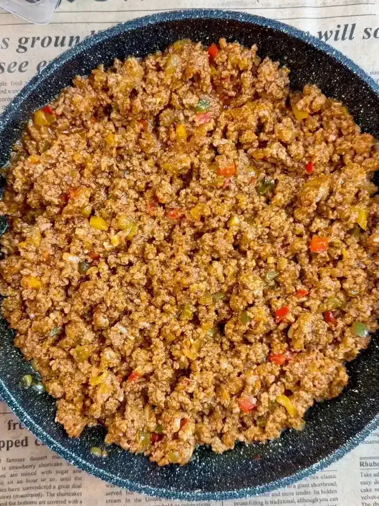 Cooking flavorful taco beef filling with onions, garlic, bell peppers, and spices for Cheesy Loaded Taco Fries, simmered until rich and thick.