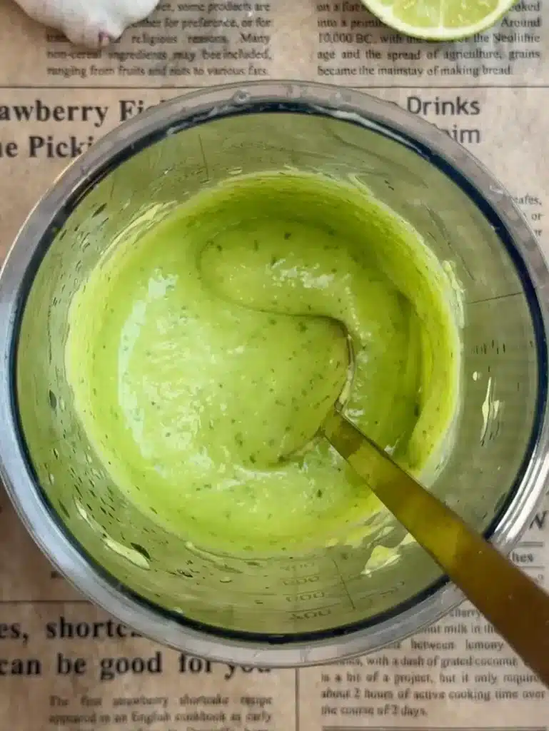Blending creamy avocado sauce for Cheesy Loaded Taco Fries with avocado, cilantro, garlic, lime juice, olive oil, salt, and pepper until smooth.